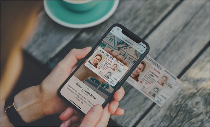 image of person holding a smart phone scanning a California ID. ID credentials are shown on the smart phone.