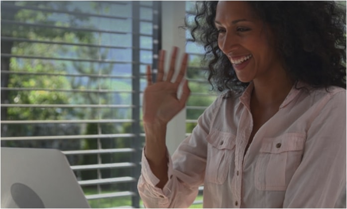 woman smiling at computer waving.