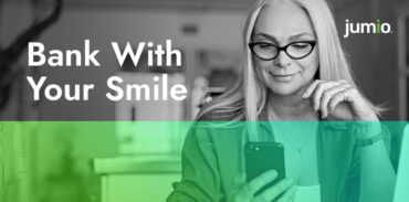 image of woman holding a phone. Woman is wearing glasses and has a watch on left hand. Text on image reads: Bank with Your Smile.