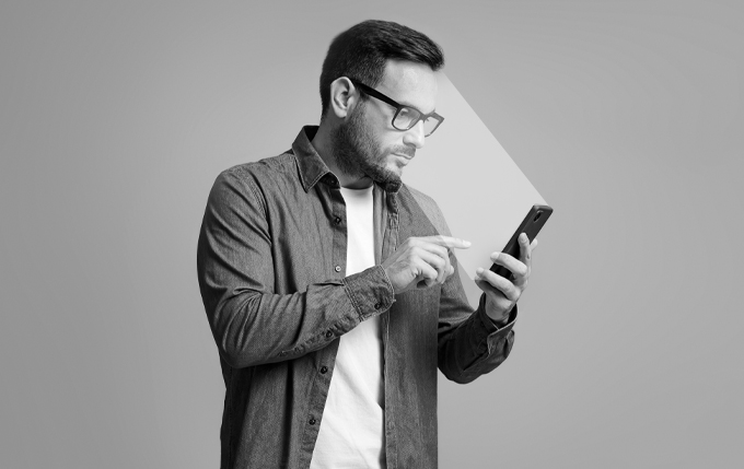 image of male holding phone getting face scanned. Image is in black and white
