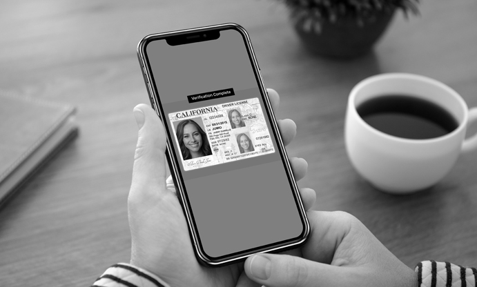 black and white image of phone screening showing ID with cup of coffee next to it.