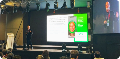 image of speaker on stage presenting Jumio slide show.
