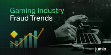 Person holding gaming chips in their left hand with a computer in the background. Text on image reads ‘Gaming Industry Fraud Trends.’