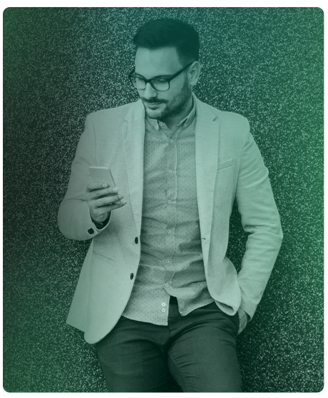 image of male holding phone in hand leaning against a wall.